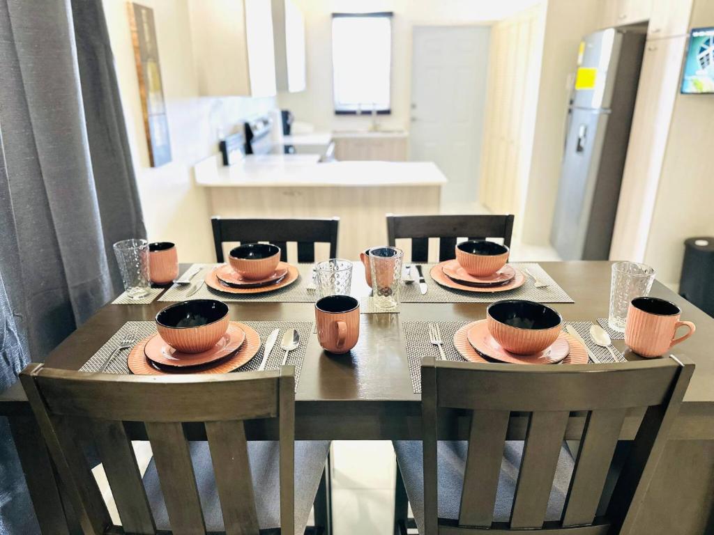 a wooden table with chairs and plates and bowls on it at Brand New - Bungalow - Ocean View - Discovery Bay in Discovery Bay