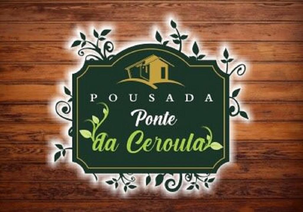 a green sign on a wooden wall at Pousada Ponte da Ceroula in Palmeiras