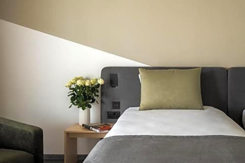 a bedroom with a bed and a vase of flowers on a table at Cavalieri Art Hotel in St. Julianʼs