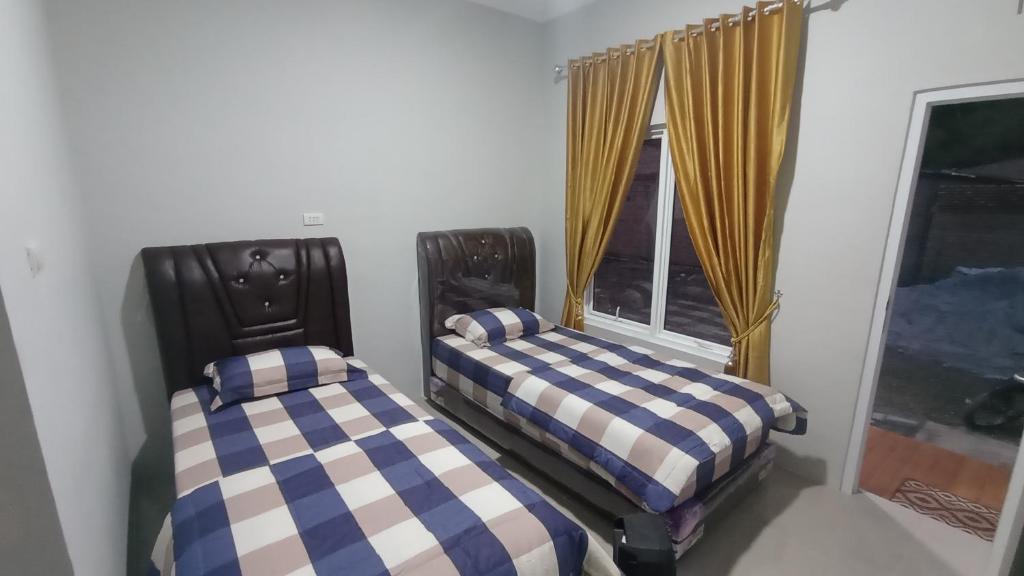 2 Betten in einem Zimmer mit Fenster in der Unterkunft Bagas Penginapan 
