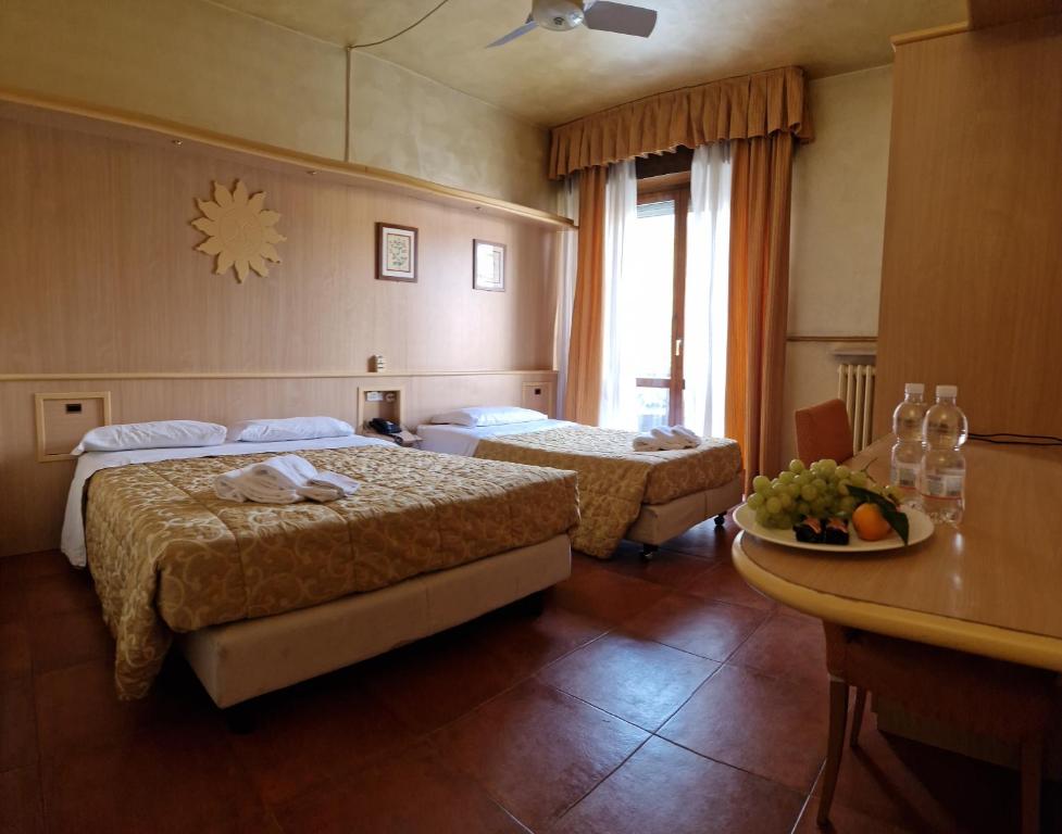 a hotel room with two beds and a table at Hotel San Giorgio in Boltiere