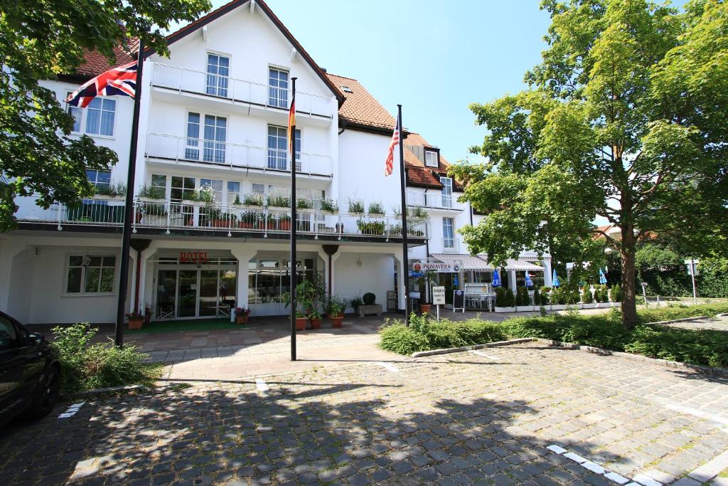 un grande edificio bianco con una bandiera davanti di Abasto Hotel Eichenau a Eichenau