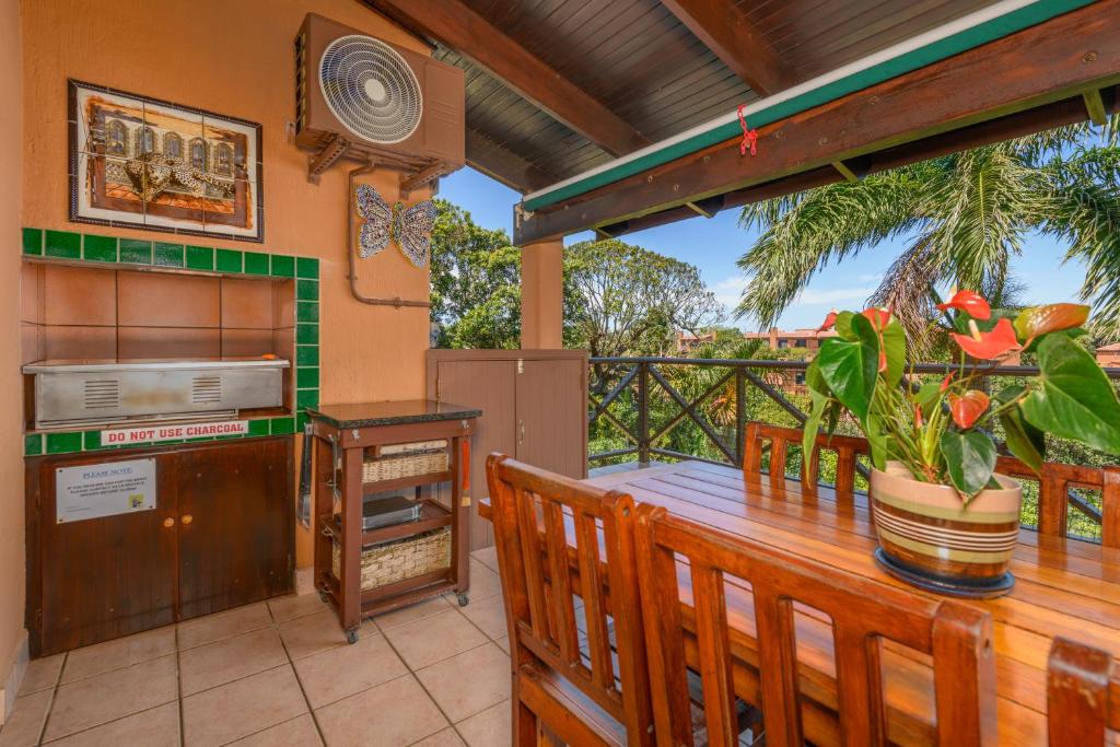 a porch with a wooden table and a kitchen at San Lameer Villa 1930 - 4 Bedroom Superior - 8 pax - San Lameer Rental Agency in Southbroom