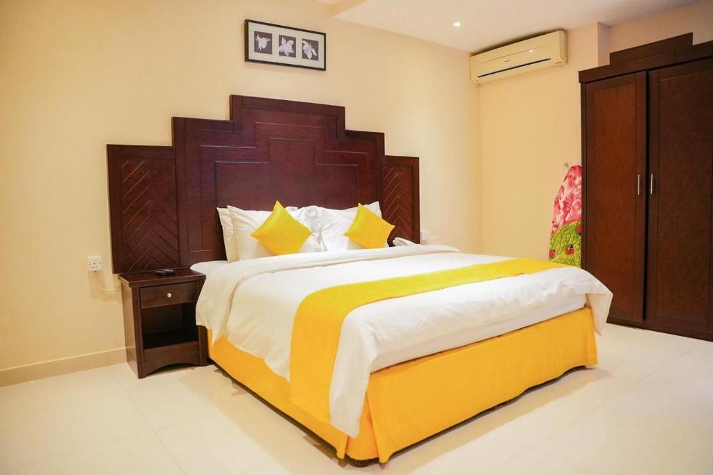 a bedroom with a large bed with a wooden headboard at Asfar Hotel Apartments in Muscat