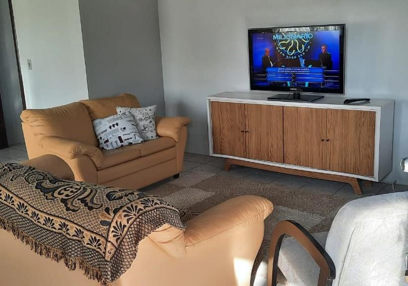 a living room with a tv on a wooden cabinet at Casa agradável, ampla com estacionamento in Tramandaí