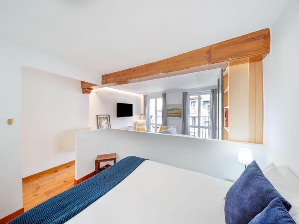 - une chambre avec un lit blanc et un grand miroir dans l'établissement Apartamento Mercaderes, à Pampelune