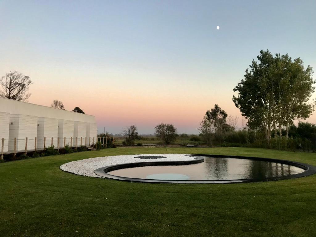 um lago no meio de um campo com um edifício em Tijosa Eco-House Camp em Ovar