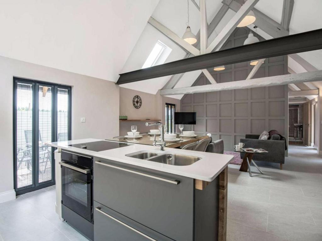 a kitchen with a sink and a living room at dairy cottages in Wimborne Minster