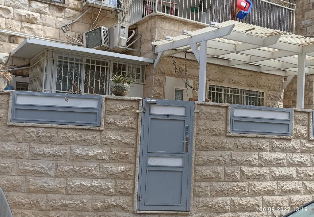 eine Steinmauer mit blauen Türen und einem Gebäude in der Unterkunft Yair room apartment in Jerusalem