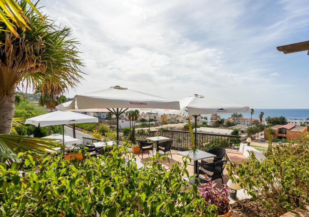 a patio with tables and umbrellas and the ocean at La Tartana Hotel Boutique in La Herradura