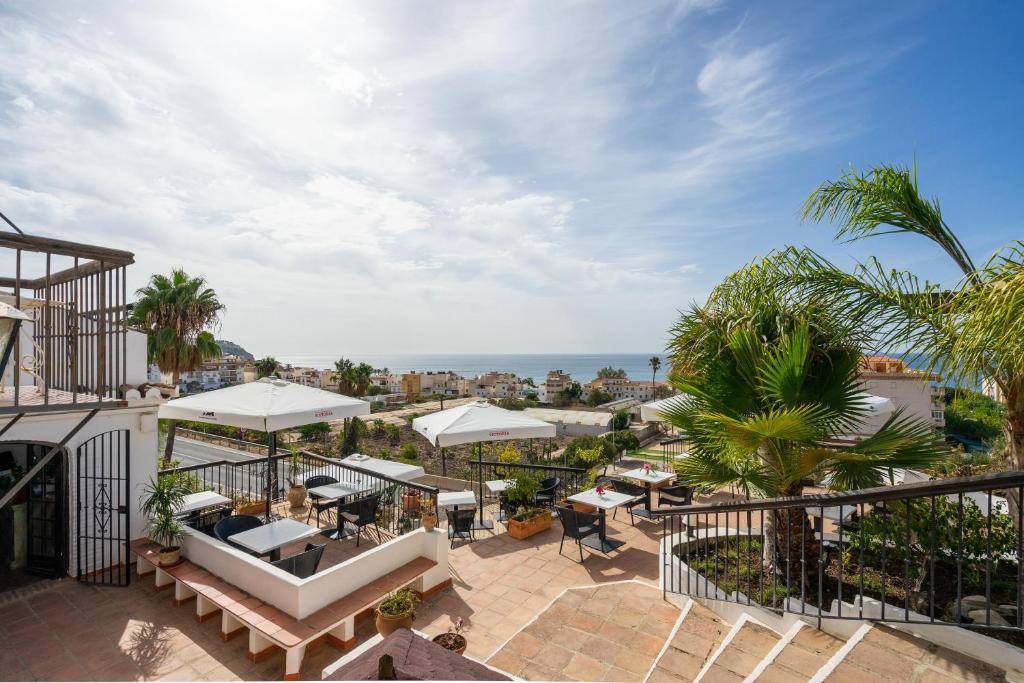 an outdoor patio with tables and umbrellas on a building at La Tartana Hotel Boutique in La Herradura