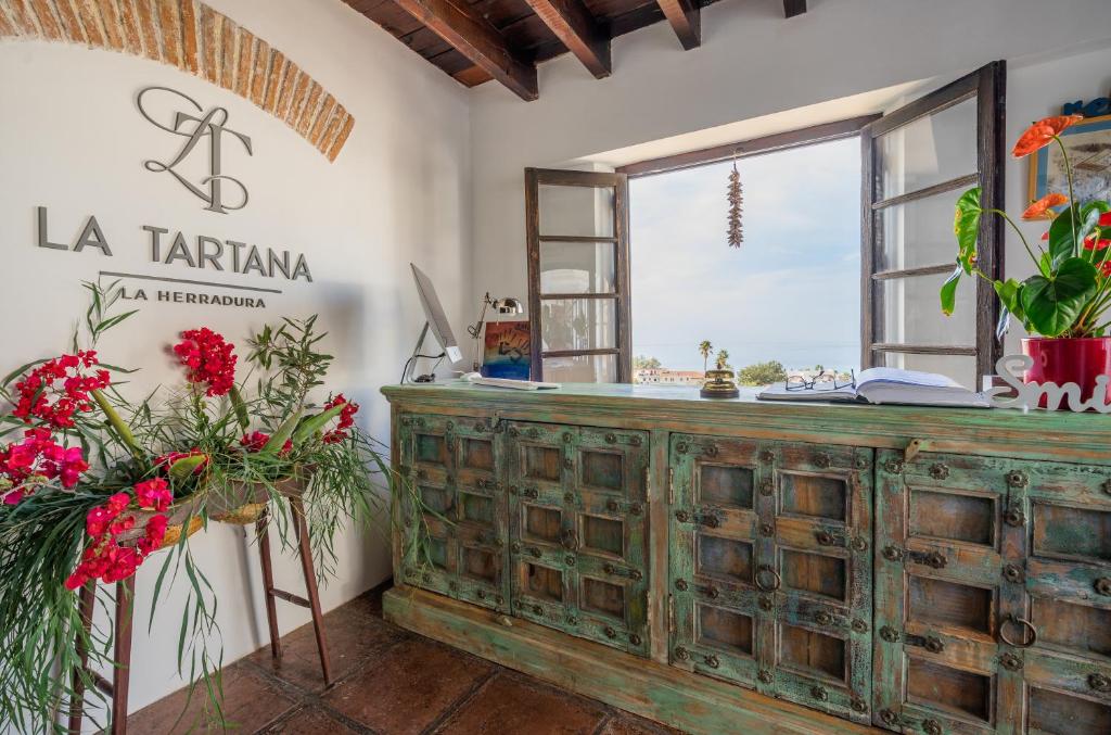 a wooden chest in a room with a window and flowers at La Tartana Hotel Boutique in La Herradura