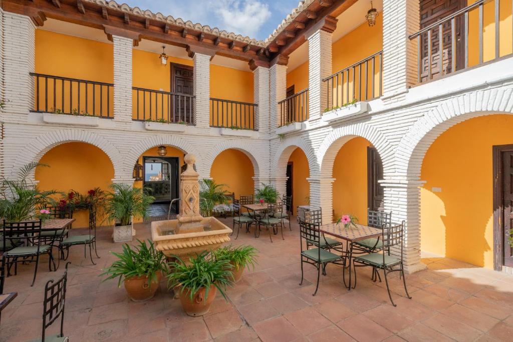 um pátio exterior com mesas e cadeiras num edifício em La Tartana Hotel Boutique em La Herradura