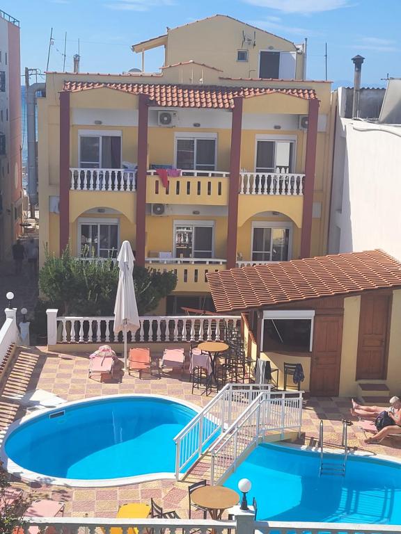 a house with a swimming pool in front of a building at Agali Hotel in Limenaria