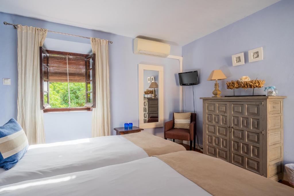 a bedroom with two beds and a dresser and a window at La Tartana Hotel Boutique in La Herradura