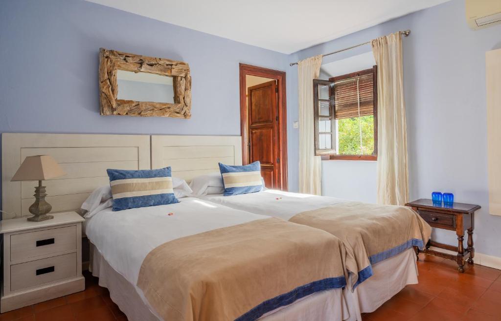 a bedroom with a large white bed with blue pillows at La Tartana Hotel Boutique in La Herradura