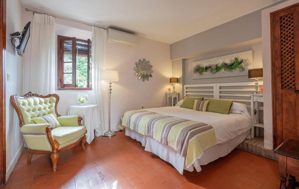 a bedroom with a bed and a chair at La Tartana Hotel Boutique in La Herradura