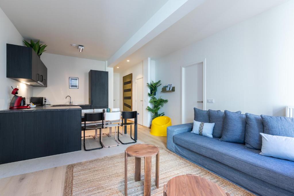a living room with a blue couch and a kitchen at Smartflats - Rogier Brussels in Brussels