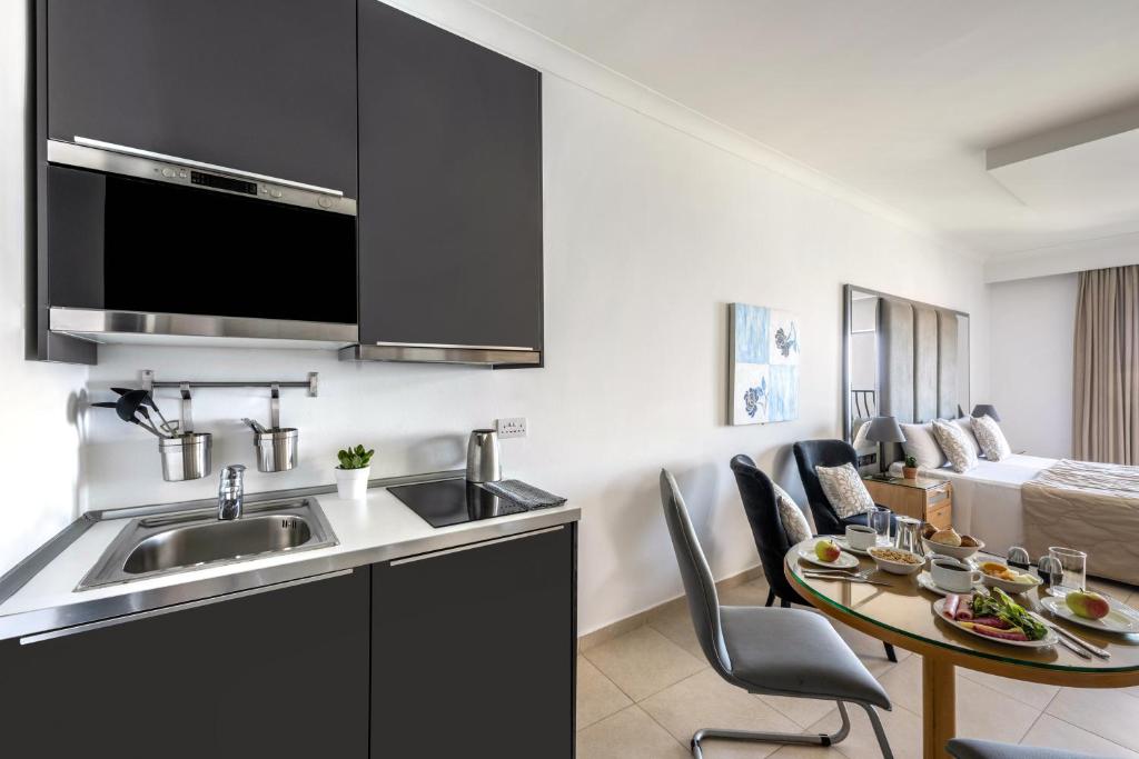 a kitchen with a sink and a table with chairs at Plaza Regency Hotels in Sliema