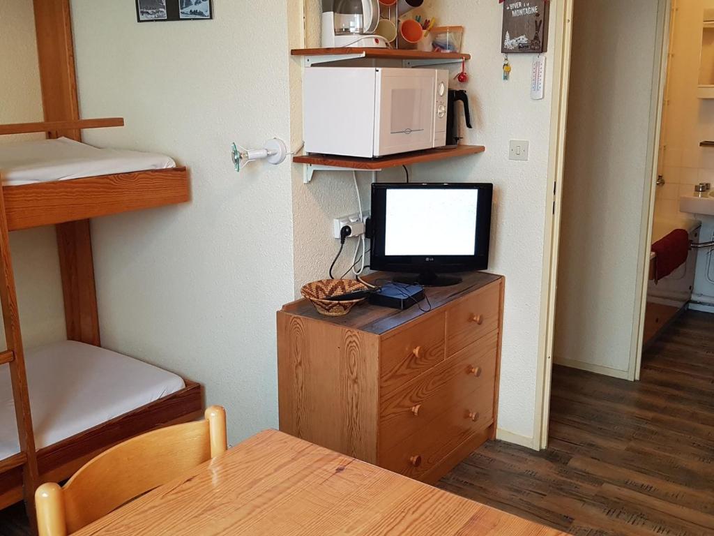 Cette chambre dispose d'une télévision sur une commode en bois avec une table. dans l'établissement Appartement Le Pleynet, 1 pièce, 3 personnes - FR-1-557A-51, à La Ferrière