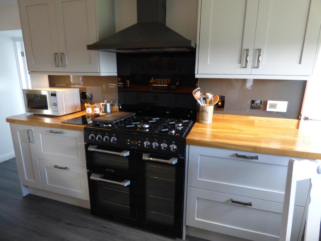 a kitchen with a black stove and a microwave at Sighthill Cottage, North Tolsta in Stornoway