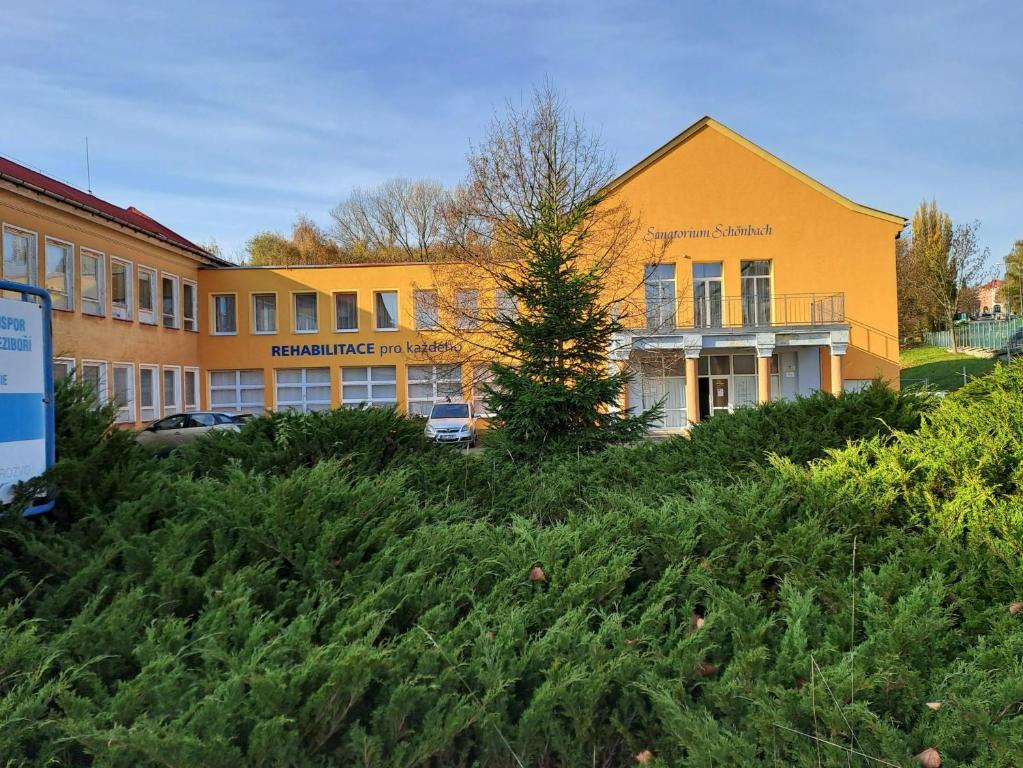 un edificio escolar con una colina pastosa delante de él en Lázně Meziboří, en Meziboři