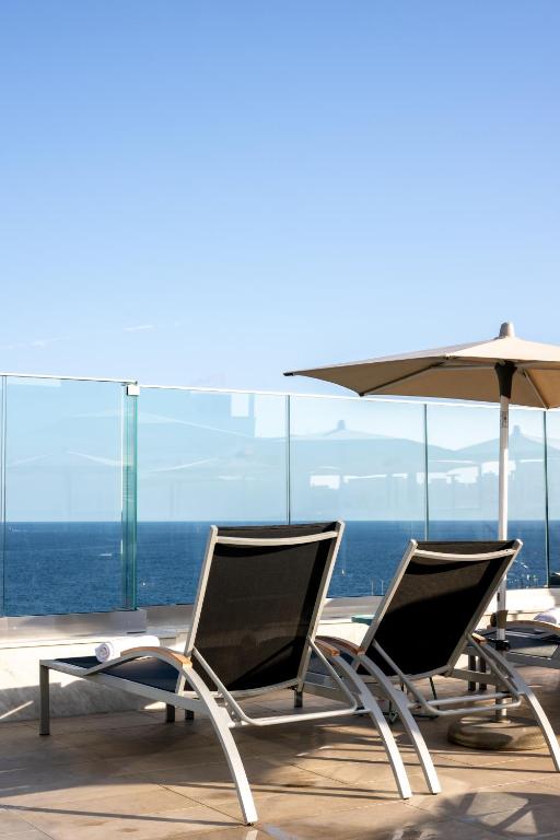 two chairs and an umbrella on a balcony with the ocean at Plaza Regency Hotels in Sliema