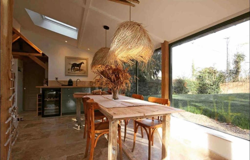 een eetkamer met een houten tafel en stoelen bij Le loft Normand avec piscine chauffée in Saint-Antonin-de-Sommaire