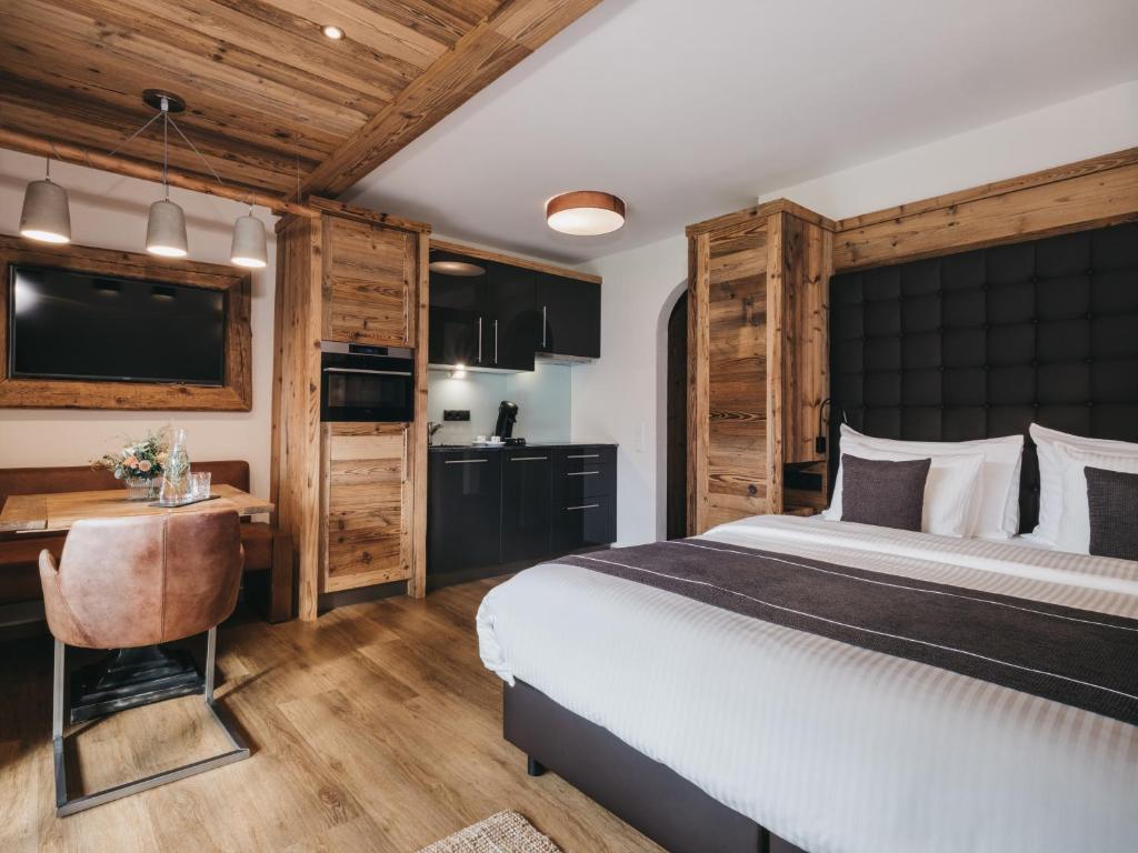 a bedroom with a bed and a desk and a television at VAYA Kaprun inklusive Zell am See Kaprun Sommer Karte in Kaprun