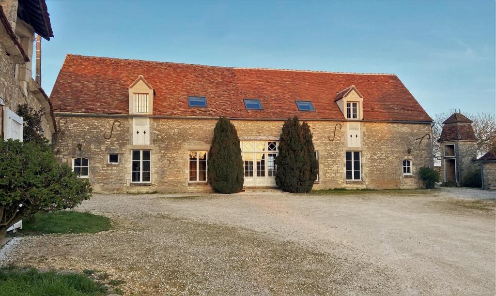 un gran edificio de ladrillo con techo rojo en LA CHARMILLE Jolie maison de campagne 14 personnes piscine calme, en Entrains-sur-Nohain