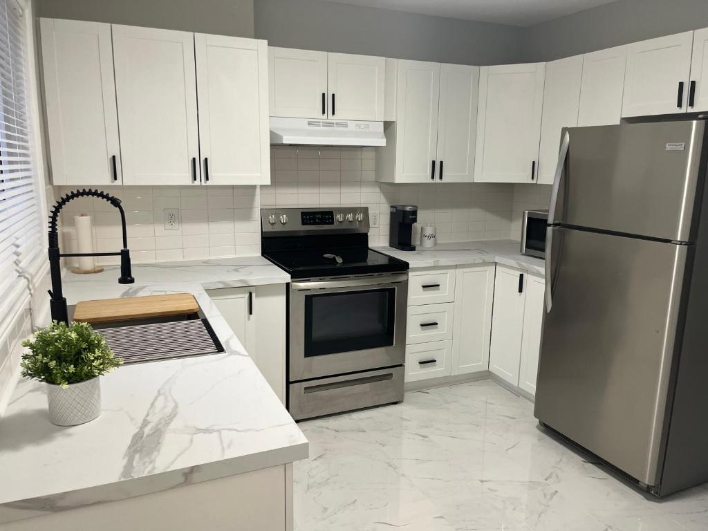 a kitchen with white cabinets and a stainless steel refrigerator at Casa LACK - Tranquila Suites 2 in Ottawa