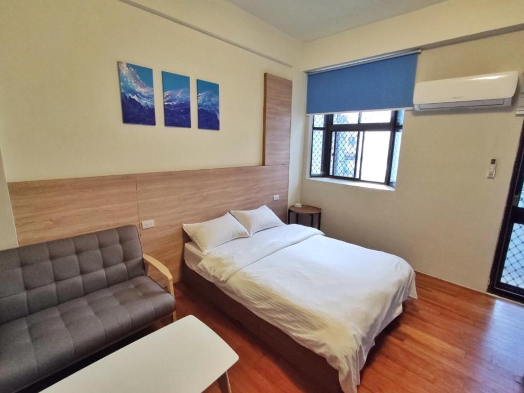 a bedroom with a bed and a couch at 翼想旅宿-2022營運車站前花蓮民宿 in Hualien City