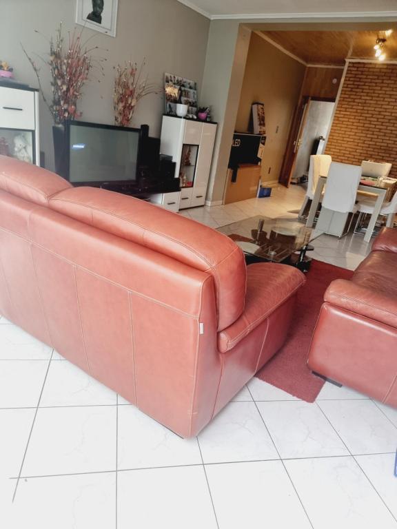 - un salon avec un canapé en cuir brun et une télévision dans l'établissement maison de vacances, à Halle