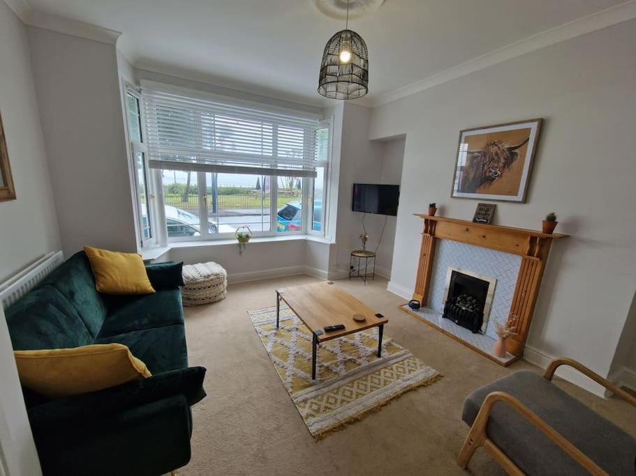 sala de estar con sofá y chimenea en Lovely Seafront Apartment with Garden, en Swansea