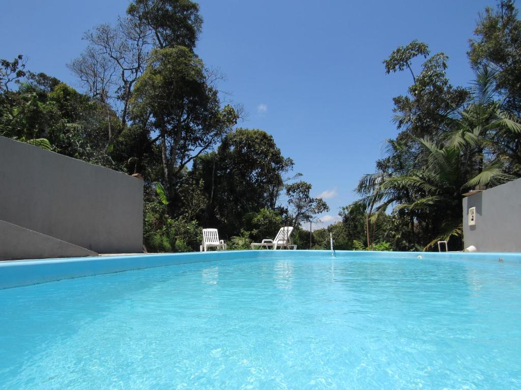 ein Pool mit blauem Wasser und zwei Stühlen in der Unterkunft Rec. Harmonia Wi-Fi Piscina Churrasqueira Lareira in Juquitiba