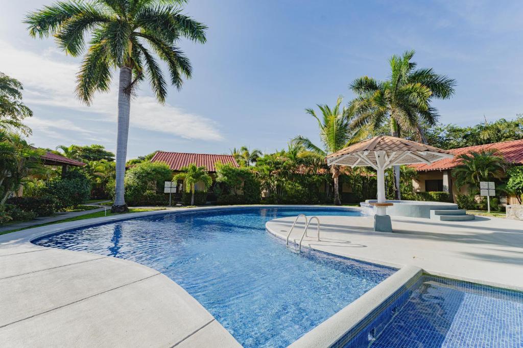 uma piscina com palmeiras num quintal em Villagio 30B -Condo near Playa Potrero em Potrero