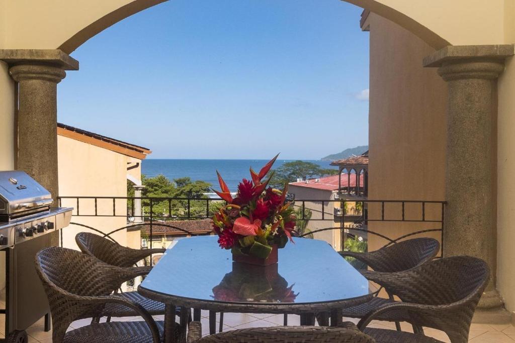 a table with a vase of flowers on a balcony at Sunrise 20- 3 Bedroom Ocean View Penthouse Condo in Tamarindo