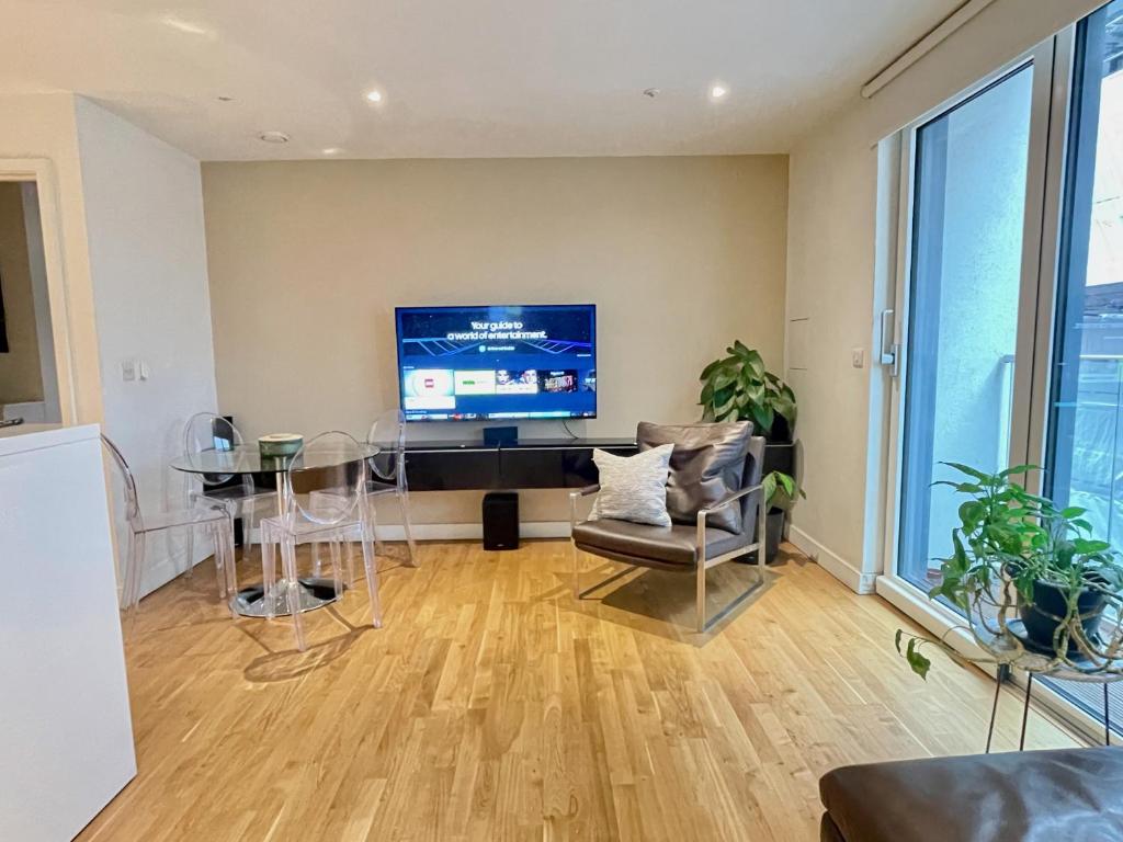een woonkamer met een televisie en een tafel en stoelen bij Westminster-Gem in Londen