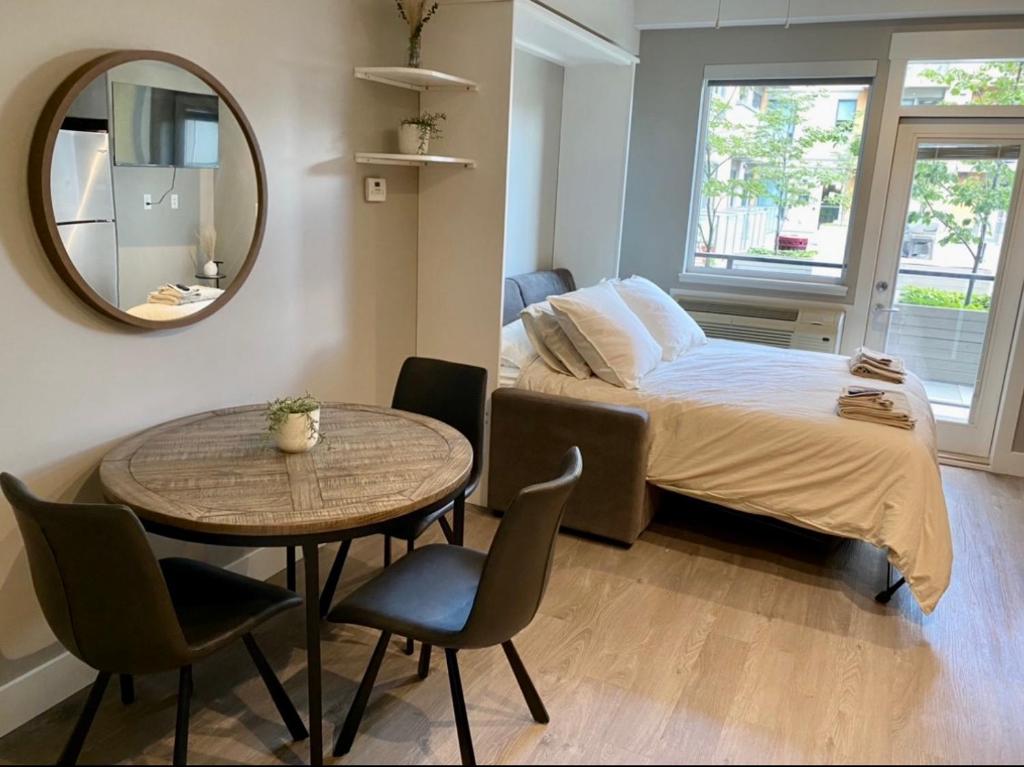 1 dormitorio con cama, mesa y espejo en Modern and cozy Courtyard View, en Kelowna