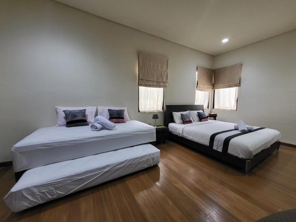 two beds in a room with wooden floors and windows at Villa Vimala Hills Semeru in Bogor