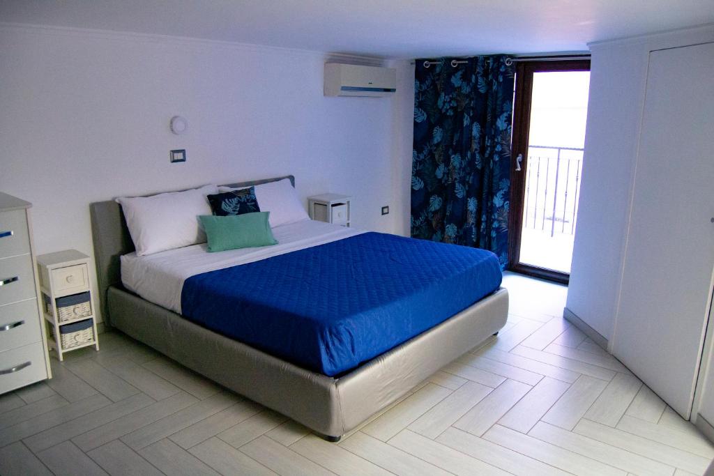 sypialnia z łóżkiem z niebieską pościelą i oknem w obiekcie Luan House w mieście San Giorgio a Cremano