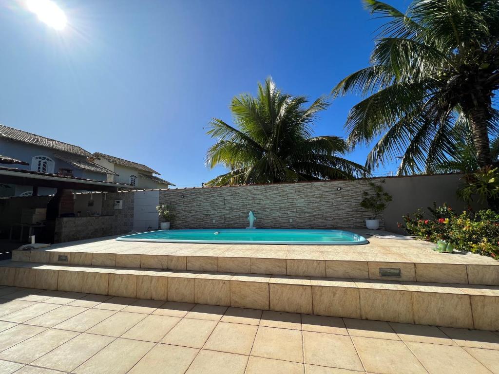 a swimming pool in a backyard with palm trees at Nosso Repouso Saquarema - Casa inteira com Piscina,churrasqueira privativos, Wi-fi,900m da praia, Tv-Smart. in Saquarema