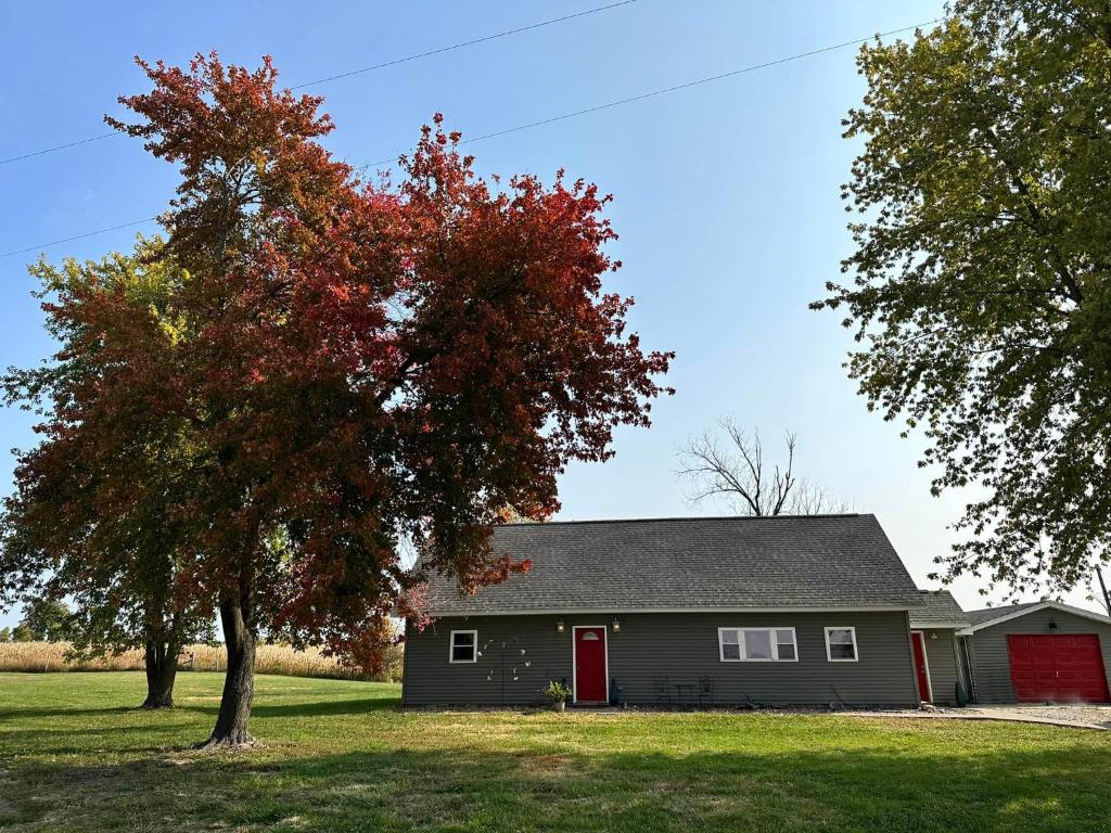una casa gris con una puerta roja y un árbol en The Getaway 