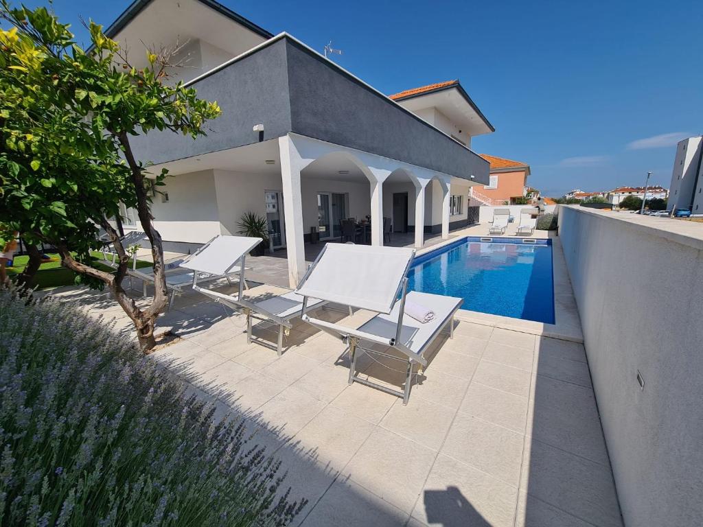 eine Terrasse mit Stühlen und einem Pool in der Unterkunft Villa Sabine in Trogir