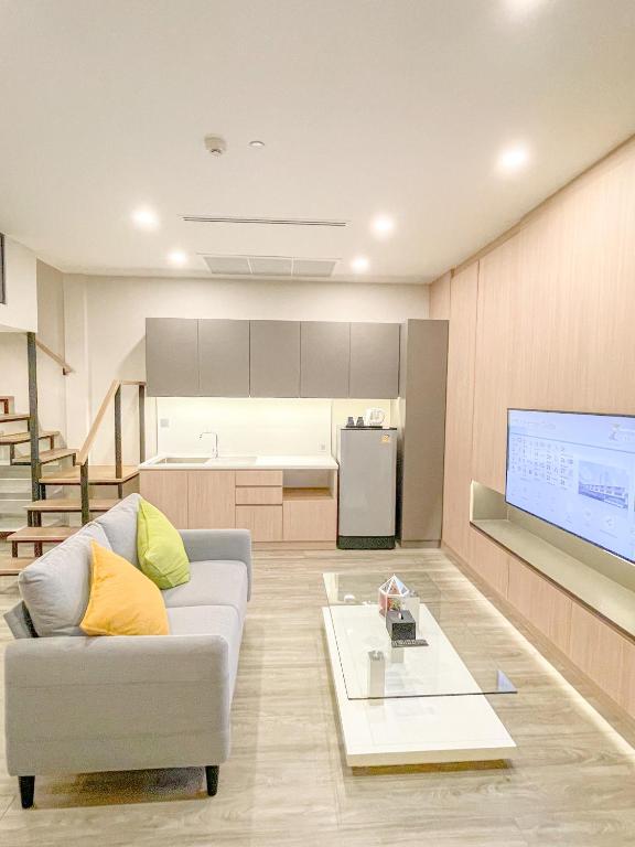 An open-plan suite with a sofa, television, kitchenette, refrigerator, and staircase.