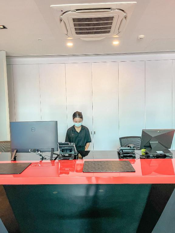 A reception desk with two computer workstations and a staff member behind it.