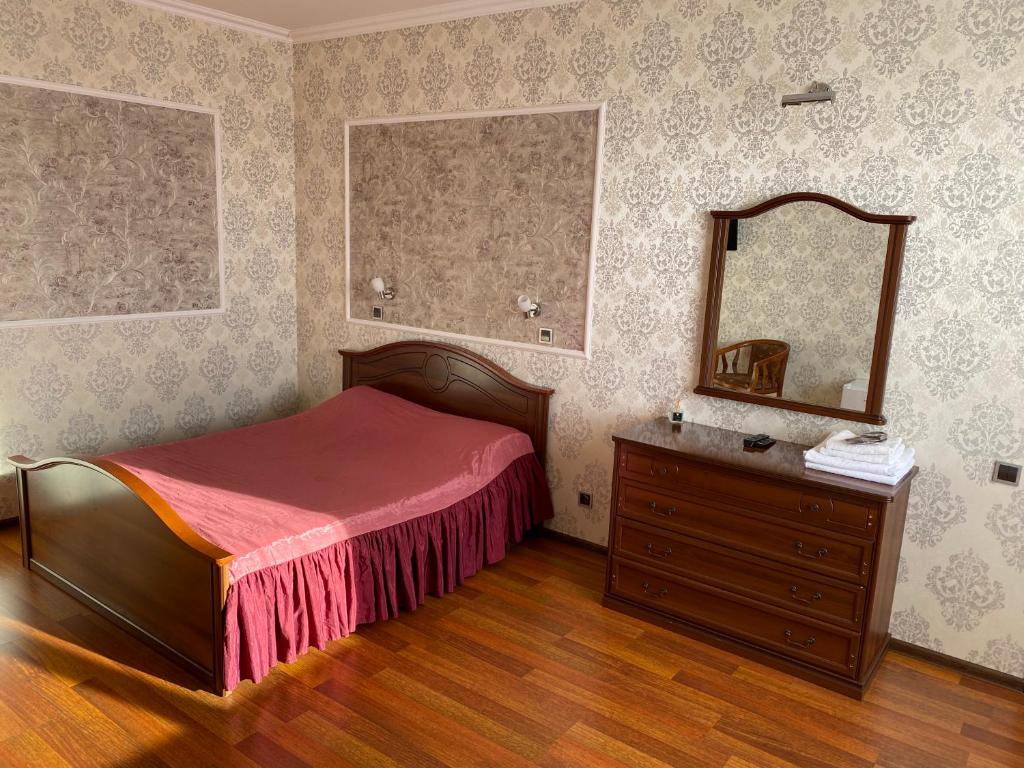 a bedroom with a bed and a dresser and a mirror at Aquarius in Podgortsy