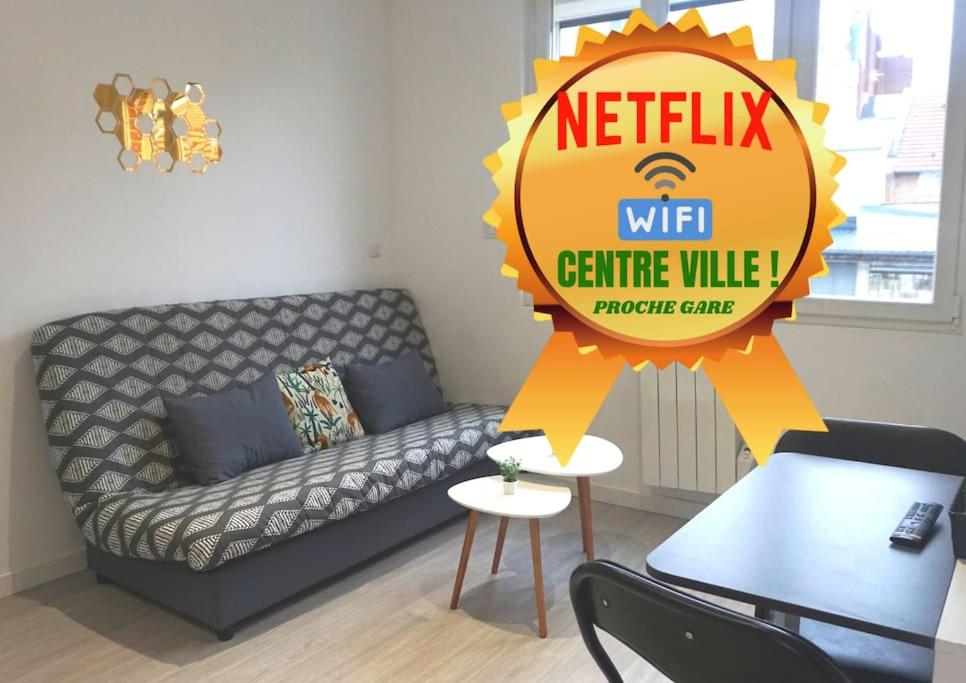 sala de estar con sofá y cartel en Cosy T2 Wifi Parking Proche gare CENTRE VILLE en Saint-Quentin