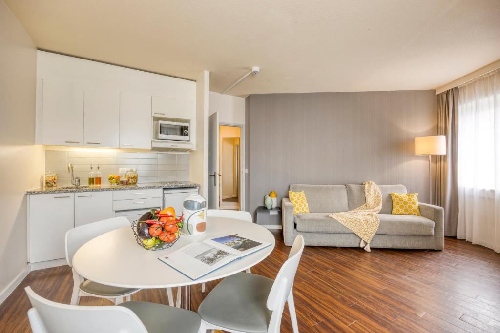 a kitchen and a living room with a table and chairs at Citadines Sainte Catherine Brussels in Brussels