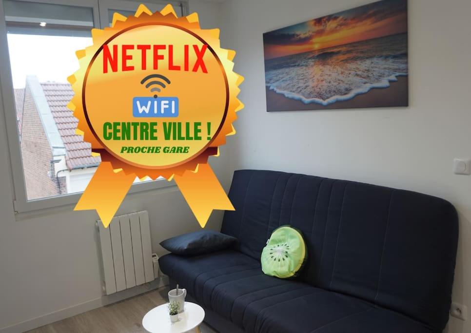 a living room with a blue couch and a sign at Coquet STUDIO TOUT ÉQUIPÉ CENTRE VILLE WIFI 2PERS in Saint-Quentin